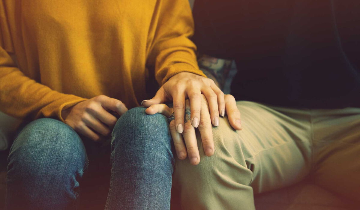 Eine Frau legt ihre Hand über die Hand eines Mannes